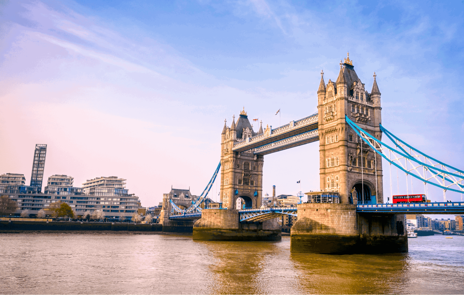 The Tower Bridge with an iconic red double decker bus crossing it